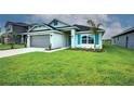 Well-maintained single-story home featuring a manicured lawn, gray garage door, and teal-colored accents at 16425 66Th E Ln, Parrish, FL 34219
