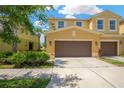 Eye-catching townhome featuring a two-car garage, surrounded by vibrant foliage and a sunny facade at 2022 Hawks View Dr, Ruskin, FL 33570