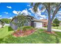 Landscaped single-story home featuring a well-maintained lawn, trimmed shrubbery, and a two-car garage at 31349 Philmar Ln, Wesley Chapel, FL 33543