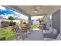 Covered patio area with outdoor seating, ceiling fan, and views of the backyard at 31349 Philmar Ln, Wesley Chapel, FL 33543