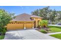 Inviting home featuring a two-car garage, manicured landscaping, and charming arched entryway at 3824 Duke Firth St, Land O Lakes, FL 34638