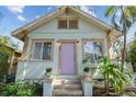 Light blue house with a charming purple door, complemented by potted plants and manicured landscaping at 535 6Th N St, St Petersburg, FL 33701