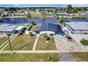 Aerial view of a waterfront home with modern architecture, a dark roof, a well kept lawn, and boat access at 551 Lindley Ter, Port Charlotte, FL 33952