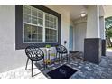 Stylish front porch seating area with modern chairs, side table, and decorative tile flooring at 710 W Peninsular St, Tampa, FL 33603