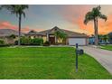 Charming single-story home at sunset featuring a lush green lawn, palm trees, and a welcoming front entrance at 8521 30Th E St, Parrish, FL 34219