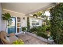 Charming front porch with cozy wicker seating, potted plants, and a stylish entrance, showcasing curb appeal at 10095 Oakhurst Rd, Seminole, FL 33776