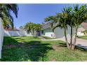 Well-maintained front yard with a white fence, palm trees, and a single-story home at 12004 Plantain Ct, Tampa, FL 33635