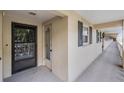 Exterior hallway shows unit 105 with a secure front door, black shutters, and outdoor lighting at 147 Bluff View Dr # 105, Belleair Bluffs, FL 33770