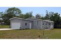 Well-maintained single-Gathering home featuring a grey facade, attached garage, and front lawn at 15591 Charmwood Dr, Hudson, FL 34667