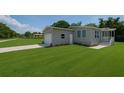 Charming gray home featuring an attached garage and a well-maintained, expansive green lawn at 15591 Charmwood Dr, Hudson, FL 34667