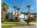 Two-story home featuring verdant lawn, mature palms, neutral stucco, and a teal garage door at 1669 Ludington Ave, Wesley Chapel, FL 33543