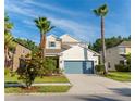 Two-story home featuring verdant lawn, mature palms, neutral stucco, and a teal garage door at 1669 Ludington Ave, Wesley Chapel, FL 33543