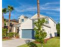 Two-story home featuring verdant lawn, mature palms, neutral stucco, and a teal garage door at 1669 Ludington Ave, Wesley Chapel, FL 33543