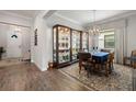 Elegant dining room features a designer chandelier, wood-look floors, and a beautiful display cabinet at 16938 Scuba Crest St, Wimauma, FL 33598