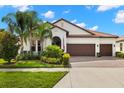 Charming home boasts a three-car garage, terracotta roof, and lush landscaping at 16938 Scuba Crest St, Wimauma, FL 33598