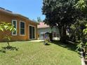 Spacious backyard with lush lawn, mature trees, and a charming outdoor grill at 1855 Briland St, Tarpon Springs, FL 34689