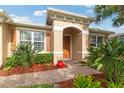 Close-up of the front entrance with an arched entryway, well-maintained landscaping, and brick walkway leading to the front door at 19418 Butterwood Ln, Lutz, FL 33558