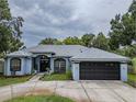 Charming blue home featuring a well-manicured lawn and a two-car garage at 22946 Brownwood Ct, Land O Lakes, FL 34639