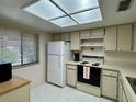 Efficient kitchen featuring essential appliances, white cabinets, and skylight at 2541 Laurelwood Dr # 8C, Clearwater, FL 33763