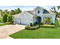 Charming single-Gathering home featuring a well-manicured lawn, 3 car garage, and lush landscaping at 26 Concord Dr, Dunedin, FL 34698