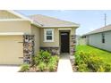 Close-up view of home's entrance featuring stone accents, neutral paint, and manicured landscaping at 3762 Mossy Limb Ct, Palmetto, FL 34221