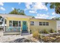 Charming yellow home featuring a welcoming turquoise front door and a cozy front porch at 6453 5Th N Ave, St Petersburg, FL 33710