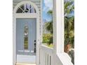 Close up of the front door entrance with a light blue door, white railings, and decorative glass at 7630 Sailwinds Pass, Port Richey, FL 34668