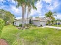 Beautiful single-story home with lush lawn, mature palm trees, and attached two-car garage at 1338 Winding Willow Dr, Trinity, FL 34655