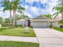 Inviting single-story home with beautiful landscaping, a well-maintained lawn, and an attached garage at 1338 Winding Willow Dr, Trinity, FL 34655