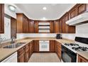 Functional kitchen with wood cabinets, tile countertops, stainless steel sink, and a gas range at 13795 Antigua Dr, Seminole, FL 33776