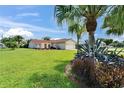 Charming front yard with tropical plants, lush green grass, and a glimpse of the single-story home behind at 1414 75Th Nw St, Bradenton, FL 34209
