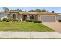 Well-maintained single-story home with a two-car garage, lush landscaping, and a brick-paved driveway at 14228 Teasdale Ave, Hudson, FL 34667