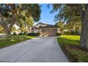 Charming single-Gathering home featuring a manicured lawn, mature trees, and a two-car garage at 2043 Wrangler Dr, Brandon, FL 33511