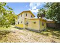 Back of the home featuring a weathered yellow exterior, small windows, and an adjacent lattice-skirted addition at 214 W Hanna Ave # A, Tampa, FL 33604