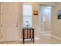 Welcoming foyer features light tile flooring, decorative cabinet, artwork and a view into the home's living spaces at 2487 Golden Pasture Cir, Clearwater, FL 33764