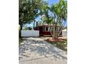 Exterior view of a red home with a long driveway and white fence, framed by mature trees at 4634 Iris N St, St Petersburg, FL 33714