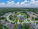 Beautiful aerial view of a home near a pond and surrounded by lush landscaping in a peaceful community at 12413 Woodlands Cir, Dade City, FL 33525