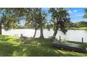 Tranquil lakeside backyard features mature trees, a fire pit, picnic table, and a small boat at 1313 Oxbridge Dr, Lutz, FL 33549
