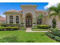 Charming home exterior with manicured lawn, lush landscaping, and arched entryway at 17921 Arbor Haven Dr, Tampa, FL 33647
