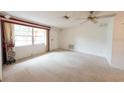 Bright living room featuring neutral carpet, large window, and a classic ceiling fan at 1808 Elmwood Dr, Oldsmar, FL 34677