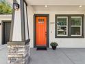 Close-up of the home's bright orange front door, with modern stone accents and stylish black trim at 2809 N 21St St, Tampa, FL 33605