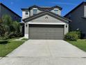 Exterior of a two-story home featuring a large garage door, simple landscaping, and neutral-colored facade at 4448 Globe Thistle, Tampa, FL 33619