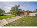 Charming home with a large grassy front yard, palm trees, and a driveway leading to a garage at 51 Cypress Dr, Palm Harbor, FL 34684