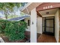 Inviting front entrance featuring a screen door, brick-tile landing, and well-maintained landscaping at 8626 Woodbridge Dr, New Port Richey, FL 34655