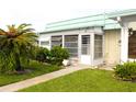 Cozy home exterior with a charming enclosed porch and lush, tropical landscaping at 101 Cambridge Trl # 194, Sun City Center, FL 33573