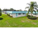 Well-maintained exterior showcasing lush green lawn, palm trees, and light blue roof and door at 101 Cambridge Trl # 194, Sun City Center, FL 33573