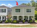 Charming exterior of a two-story home featuring a cozy front porch with green doors and neatly landscaped surroundings at 106 Cutlass Way, Oldsmar, FL 34677