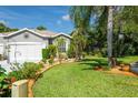 Lush front lawn with tropical landscaping and a view of the home's exterior at 12134 Tournament View Ave, New Port Richey, FL 34654