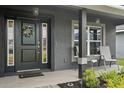 Cozy front porch with seating area, decorative wreath and pendant lighting creating an inviting entryway at 12937 Ogden Glade Rd, Dade City, FL 33525