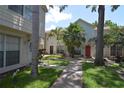 Exterior view of townhouses featuring a walkway, well-maintained lawns and lush landscaping at 13907 Fletchers Mill Dr, Tampa, FL 33613